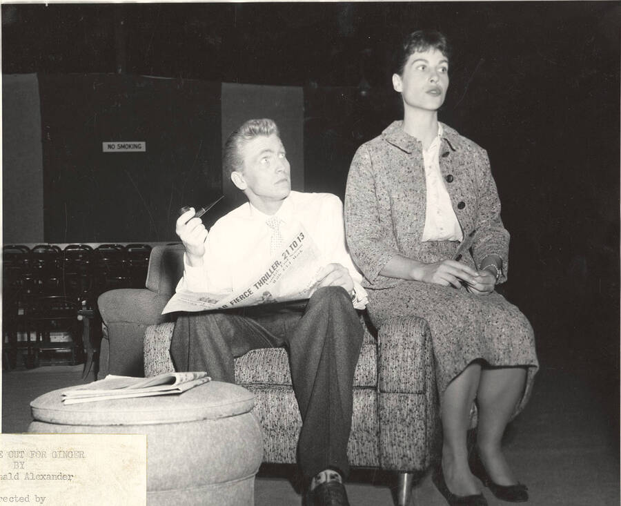 Clifford Cook smokes a pipe and Jacquelyn Bushong sits on the arm of the chair during Idaho drama's production of "Time Out for Ginger."