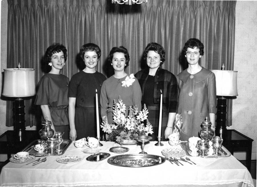 Five ladies stand behind a table set for tea. Bonnie McKay is on the left.