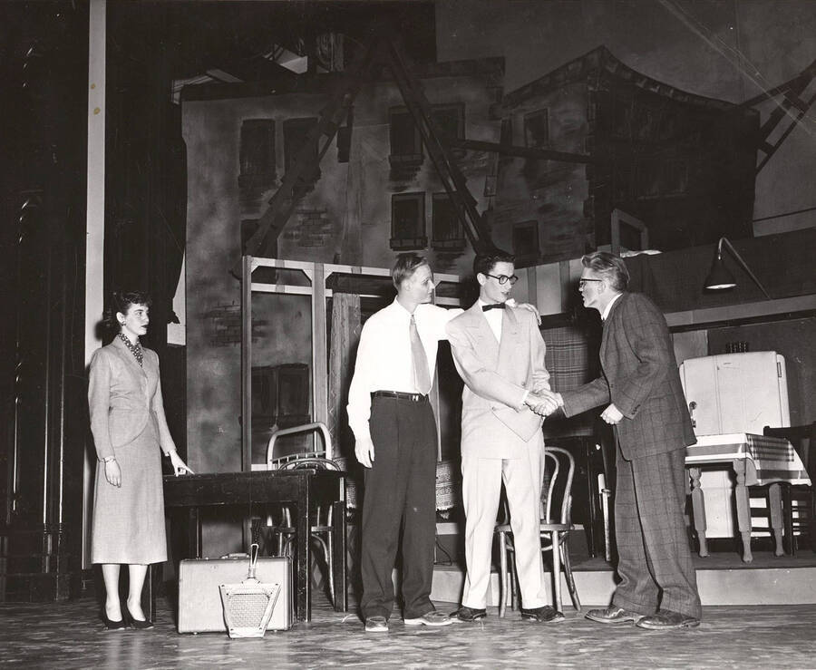 Willie, played by Tom Wright, shaking hands with his neighbor's son during a drama production of 'Death of a Salesman'.