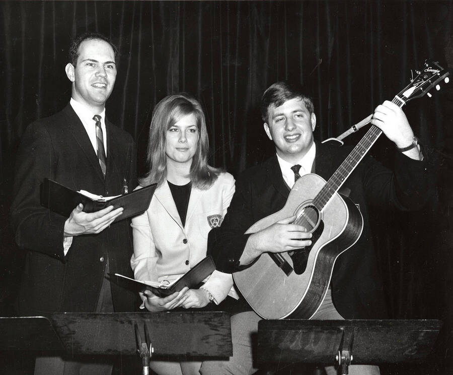 L-r: Jim Freeman, Joan Troop and Burt Pierce. One guy holding a guitar the other two individuals are holding binders.