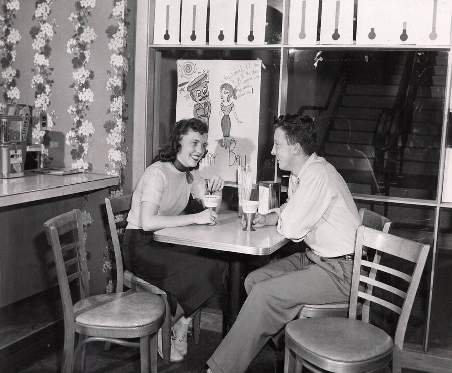 Richard Gibbs and an unidentified coed sit at a cafe table in the 1950 addition to the Student Union Building.