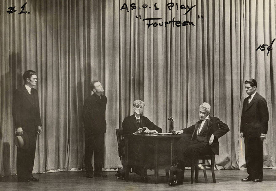 Men sit and stand on stage during the drama production of 'Fourteen,' written by Talbot Jennings