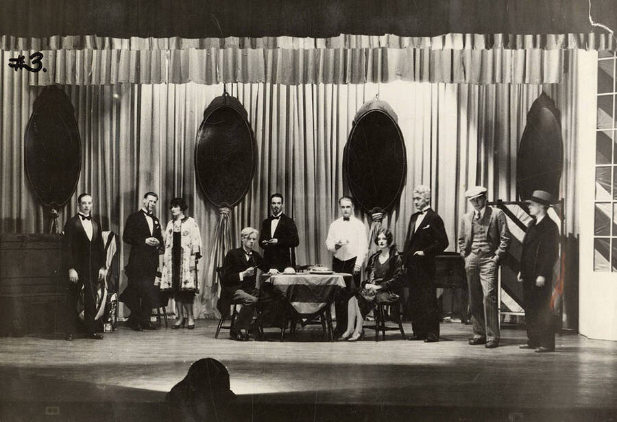 Men and women hang out around a table on stage during the drama production of 'Fourteen,' written by Talbot Jennings