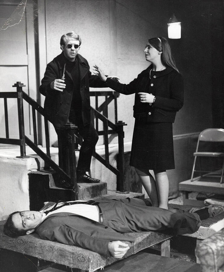 A man lays on the ground as a man and woman stand behind him during the drama production of 'Wait Until Dark,' directed by Forrest Sears.