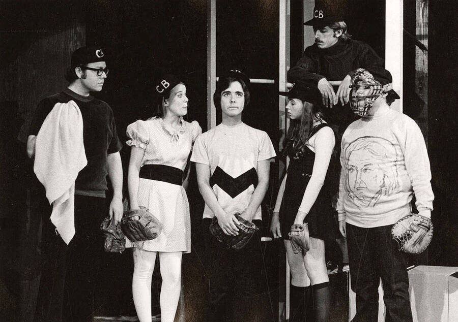 Men and women stand around looking at Charlie Brown during the drama production 'You're a Good Man, Charlie Brown.'