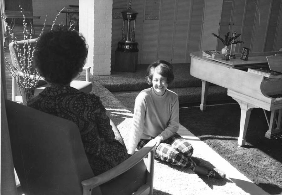 Two women sit and talk in the Kappa Alpha Theta living room.