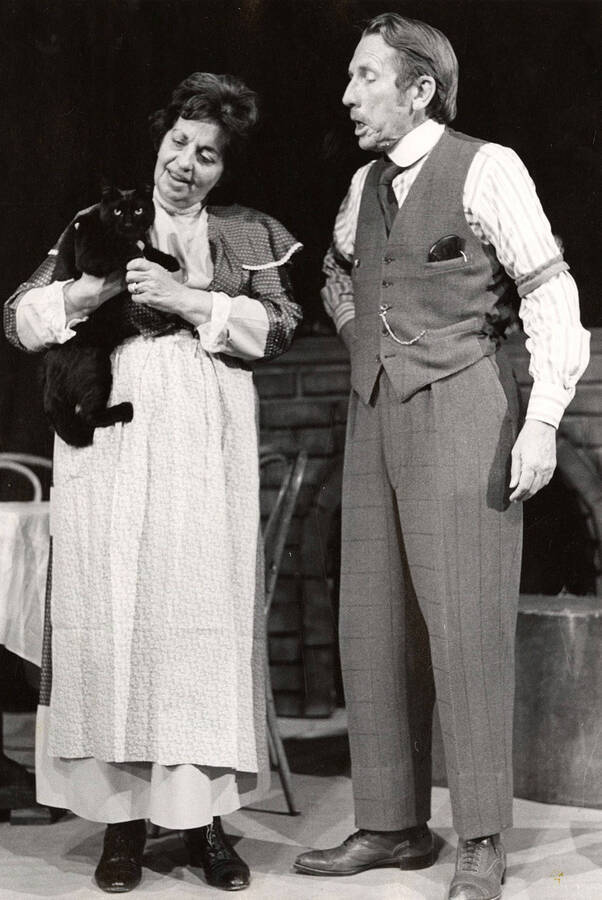 A man stands on stage with a woman, who is holding a cat, during the drama production of 'Years Ago.'