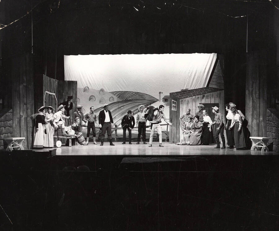 Men and women stand on stage during the drama production of 'Oklahoma.'