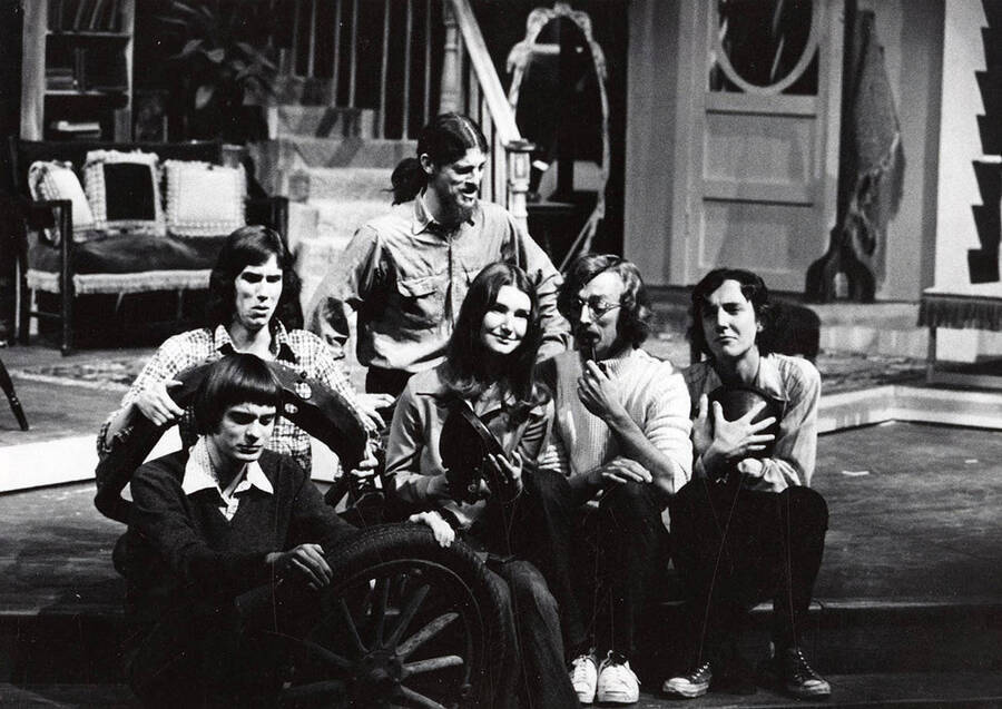 Men and women sit together backstage holding various car parts during the drama production of 'Jabberwock.'
