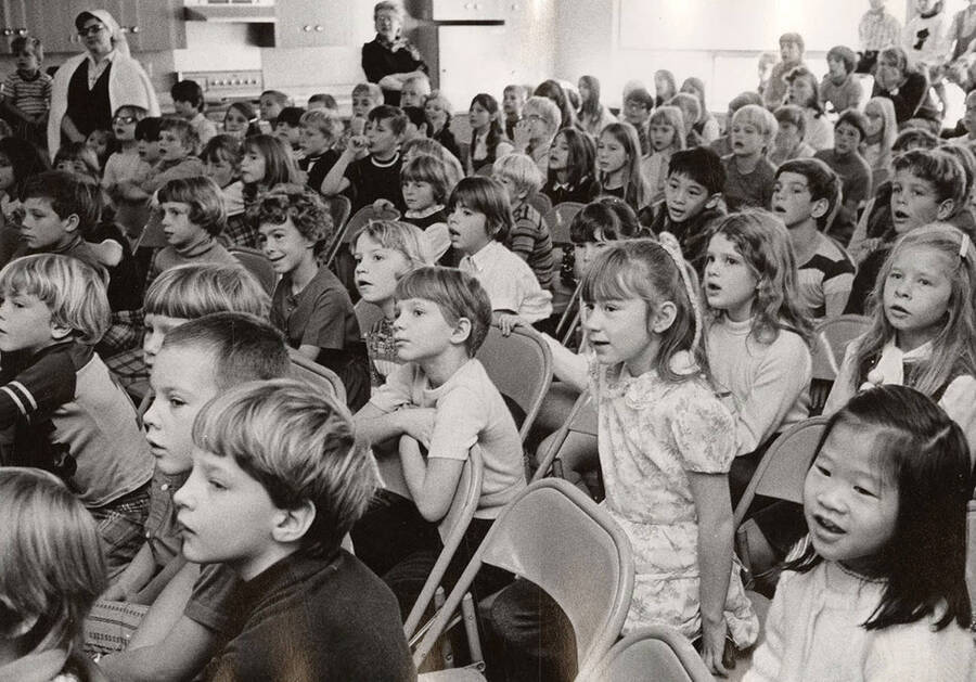 Kids sit in the audience and watch a drama production.