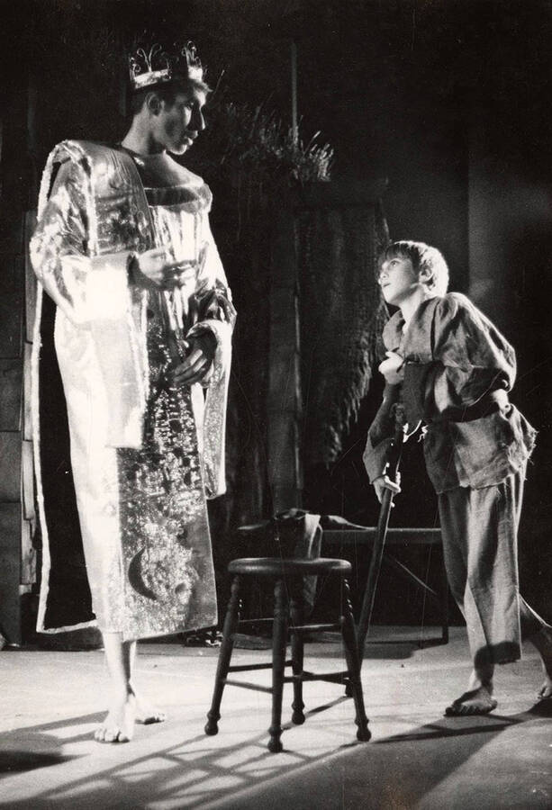 A kid on crutches approaches a king during a drama production.