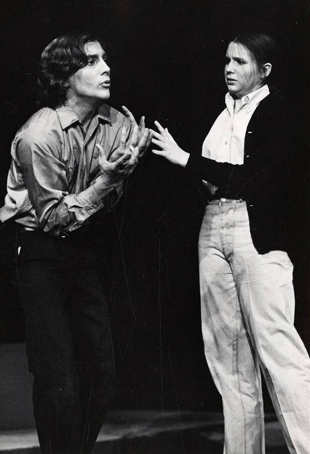 A man and woman stand on stage during a drama production.