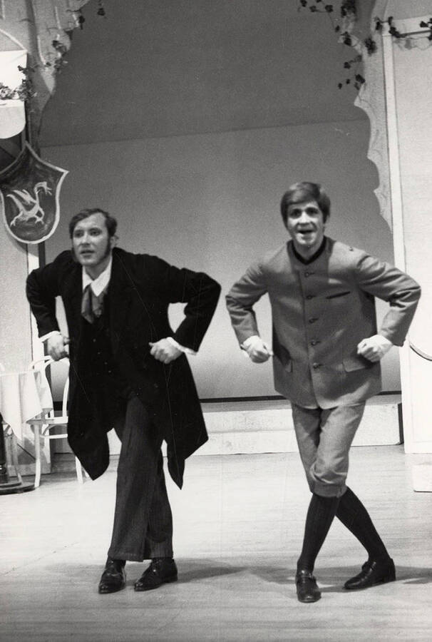 Two men dance onstage during a drama production.