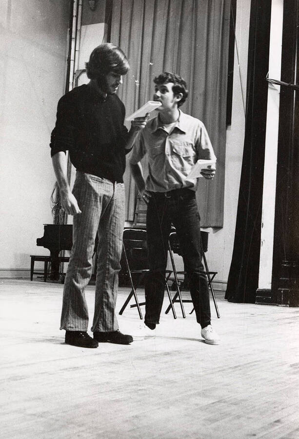 Two men read through their lines during a drama production.