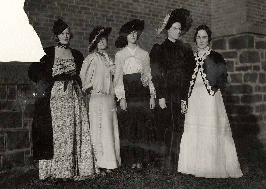 Five female University of Idaho students stand in early 20th-century period costumes.