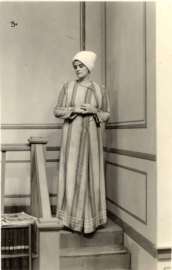 Scene from the University of Idaho drama production of 'Three Cornered Moon.' A woman can be seen standing on stairs on the set. Cast members include Helen Wilson as Elizabeth Rimplegar, Erma Lewis as Mrs. Eimplegar, Aldrich Bowler as poet, Jean Ricker as Kitty, Burnell Baker as Dr. Stevens, and Catherine Bjornstad as Jenny.