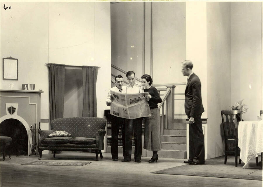 Scene from the University of Idaho drama production of 'Three Cornered Moon.' Three actors can be seen looking at a newspaper, while another man looks on. Cast members include Helen Wilson as Elizabeth Rimplegar, Erma Lewis as Mrs. Eimplegar, Aldrich Bowler as poet, Jean Ricker as Kitty, Burnell Baker as Dr. Stevens, and Catherine Bjornstad as Jenny.