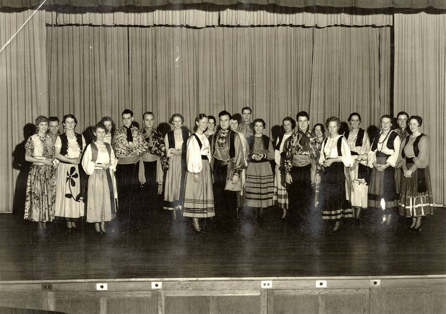 Group scene from the University of Idaho drama production of 'The Gondoliers.' The cast members can be seen dressed in costume and standing on stage.