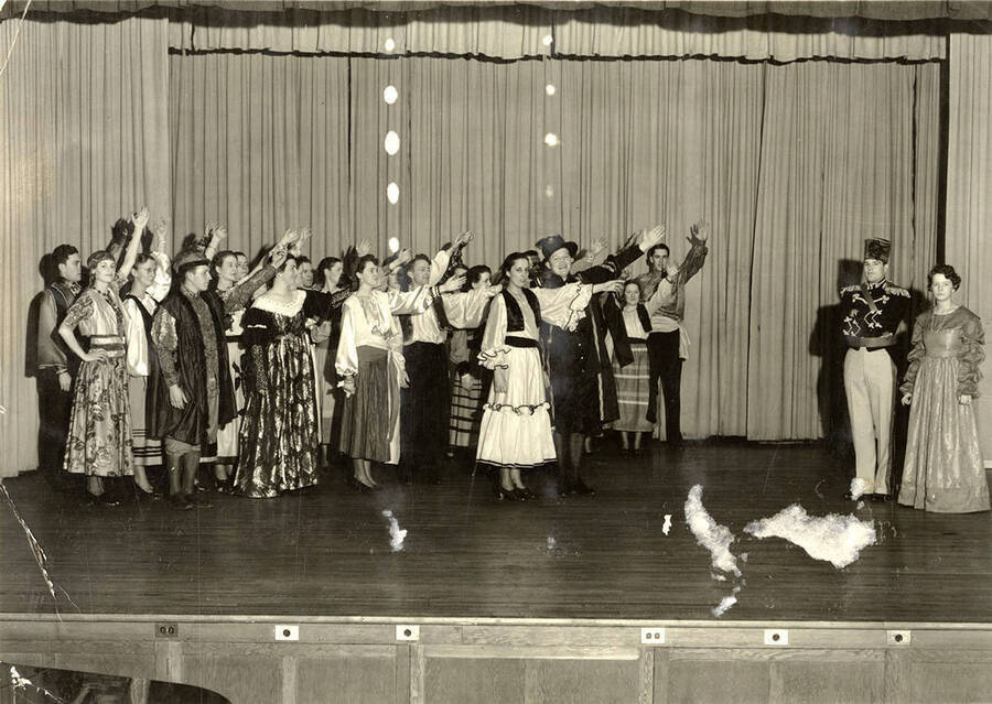 Group scene from the University of Idaho drama production of 'The Gondoliers.' The cast members can be seen dressed in costume and standing on stage.