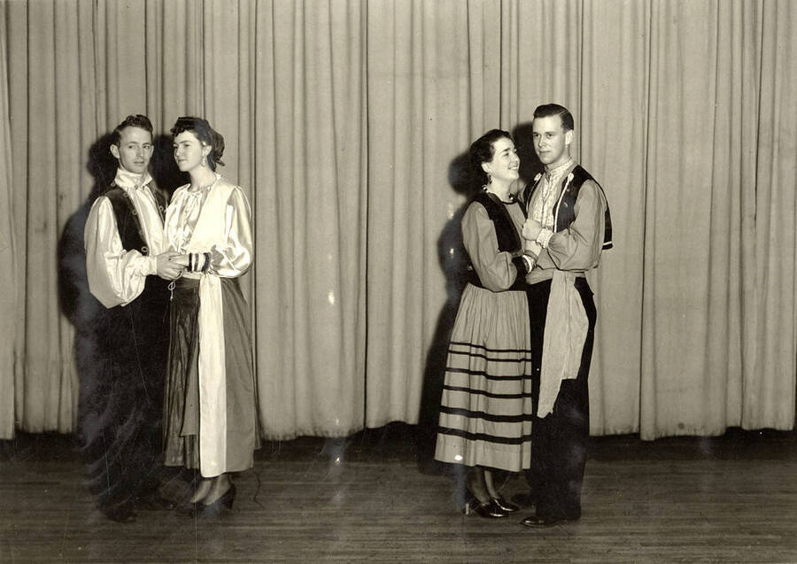 Group scene from the University of Idaho drama production of 'The Gondoliers.' The cast members can be seen dressed in costume and standing on stage. Pitured from left to right are Reginald Lyons, Dorothy Brown, Fay Pattijohn and Paul Rust.