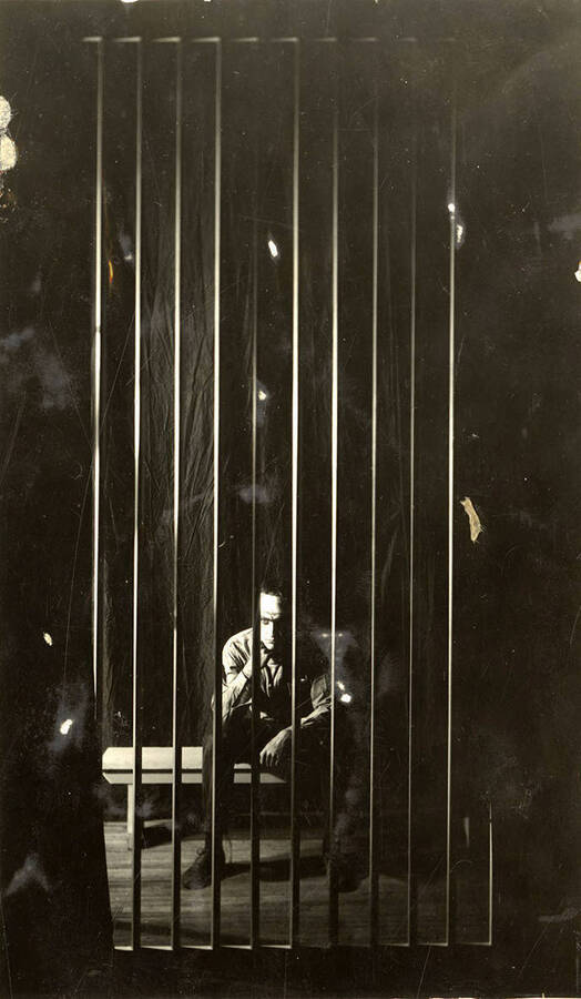 Scene during the University of Idaho drama production of 'Hairy Ape.' A man can be seen sitting behind bars on stage.