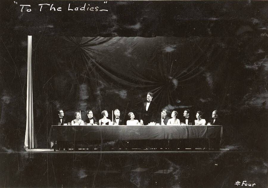 Scene from the University of Idaho drama production of 'To The Ladies.' Actors can be seen sitting at a banquet tables. Members of the cast include John Thomas as Leonard Beebe, Catherine Brandt as Elsie Beebe, Elinor Jacobs as Mrs. Kincaid, Harry Robb as John Kincaid, Howard Altnow, John Milner, Casady Taylor, Rollin Hunter, Franklyn Bovey, Winfred Janssen, Walter Pratt, and Edwin Ostroot.
