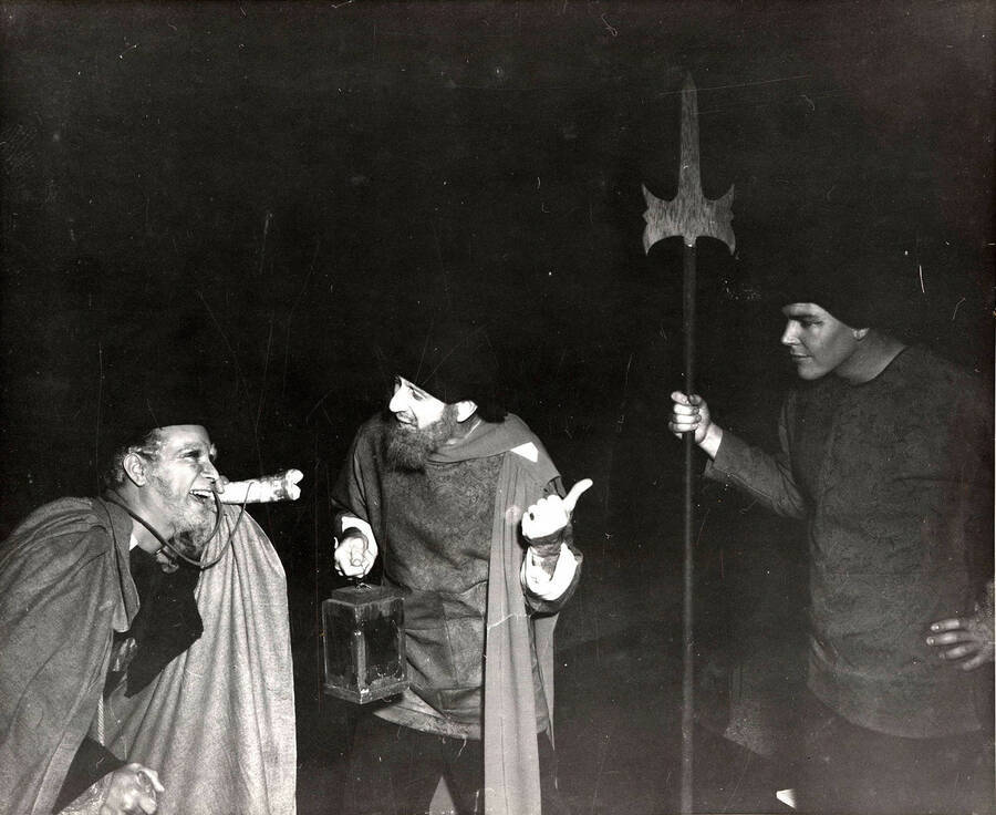 Scene during the University of Idaho drama production of 'Much Ado About Nothing.' This production was directed by Edmund Chavez. Three actors can be seen dressed in costume and conversing with each other.