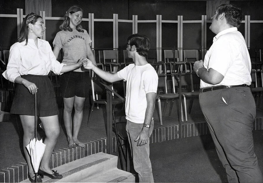 Scene during the University of Idaho drama production of 'Importance of Being Ernest.' This production was directed by Edmund Chavez. One man can be seen holding a woman's hand.
