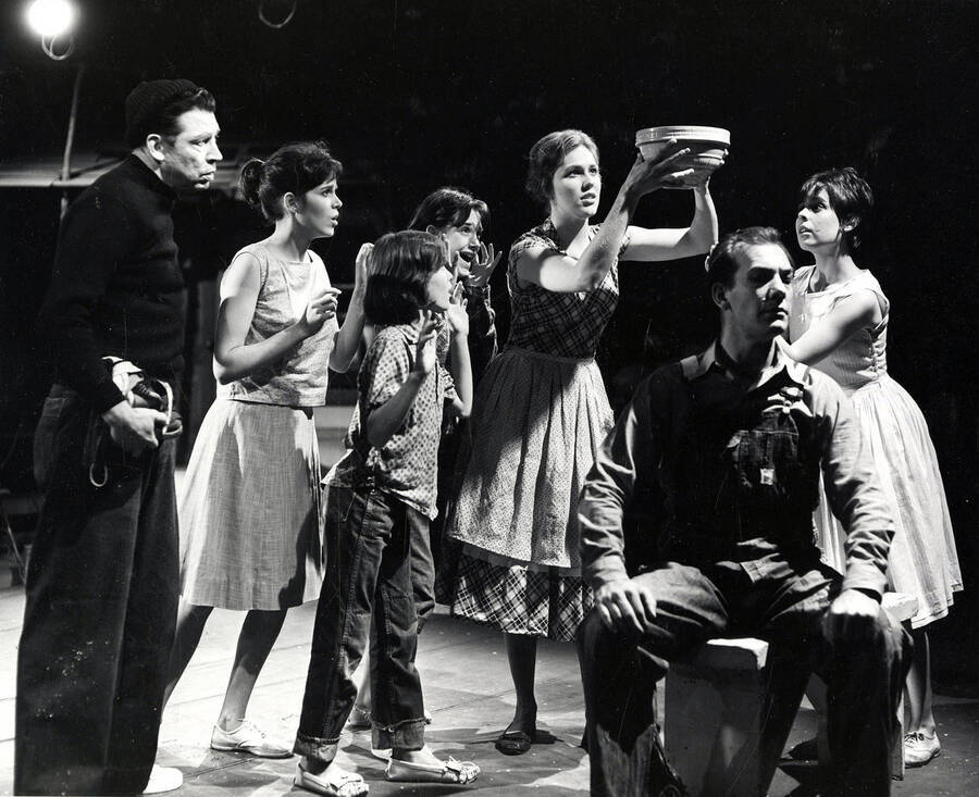 Scene from the University of Idaho drama production of 'The Great Big Doorstep.' This production was directed by Jean Collette. A woman can be seen holding a bowl above her head as the other actors look on.