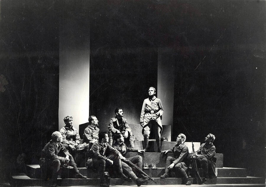 Scene from the University of Idaho drama production of 'Paths of Glory.' This production was directed by Jean Collette. A man can be seen standing on stage, while other actors look on.