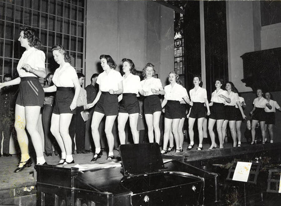 Scene from the University of Idaho drama production of 'Gee-Eyes Right.' A group of women are wearing matching costumes and seem to be dancing.