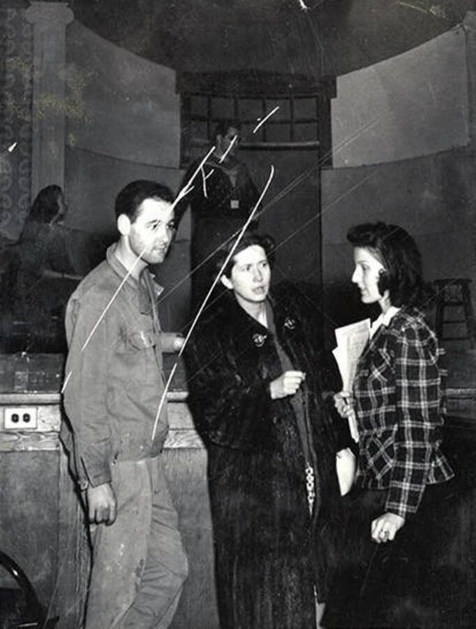 Scene from the University of Idaho drama production of 'Gee-Eyes Right.' Three cast members can be seen talking to each other.
