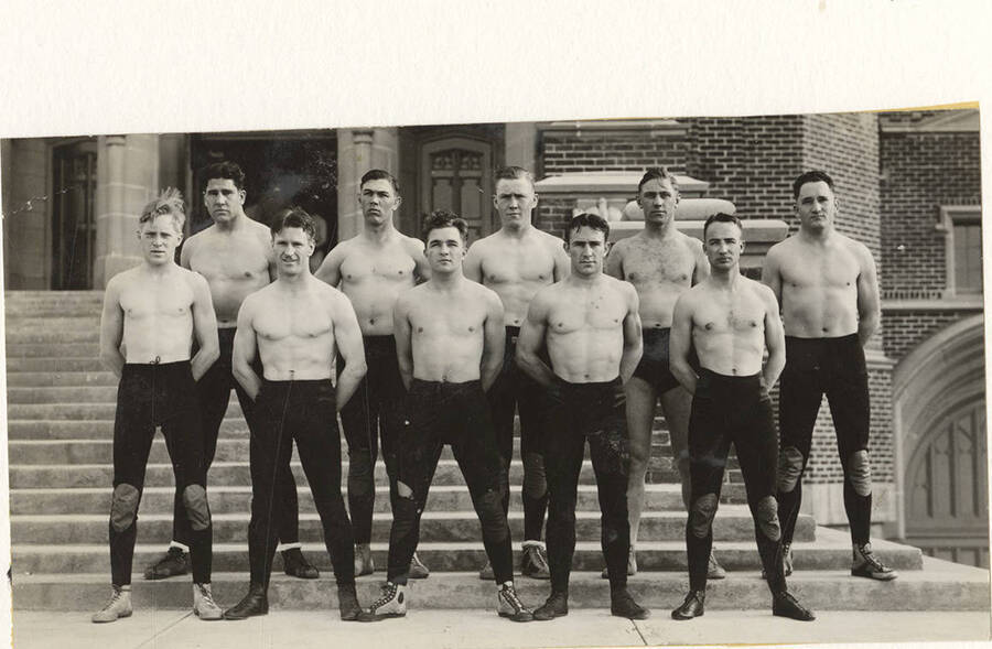 The 1932 Idaho Wrestling team posing shirtless on the steps of the Memorial Gymnasium for a team photograph.