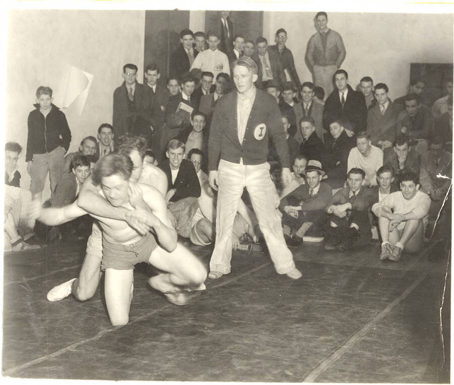 Unnamed Idaho wrestlers train in the middle of a cluster of onlookers.