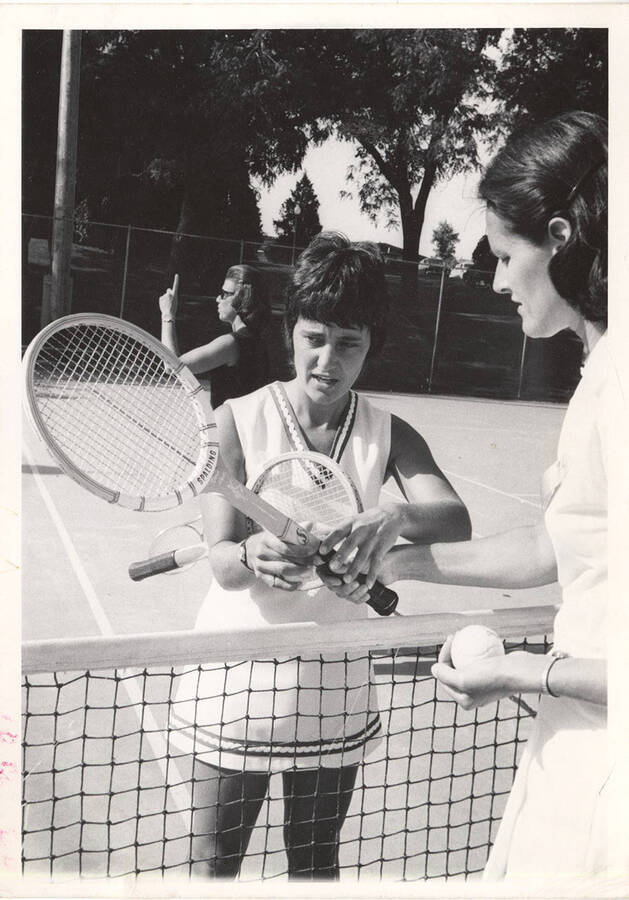 An unnamed women's Tennis instructor demonstrates the correct grip to a player.