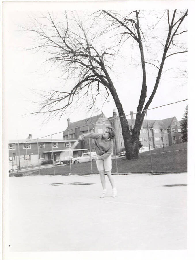 An unnamed women's Tennis player connects on a serve at practice near Campus Drive.