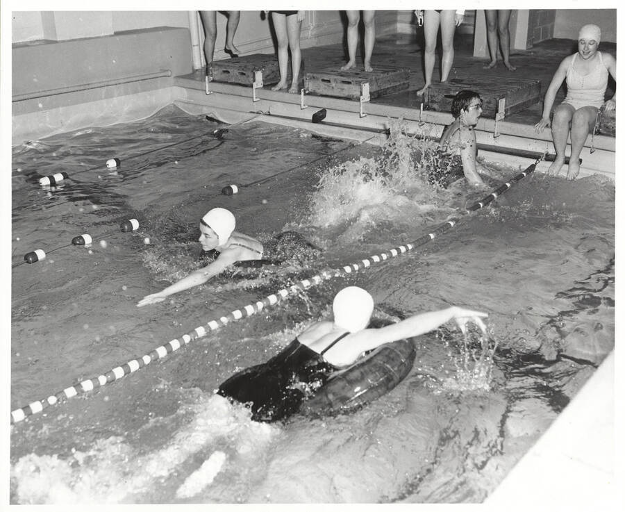Idaho women's swimmers using inner-tubes during an event in Memorial Gymnasium's basement.