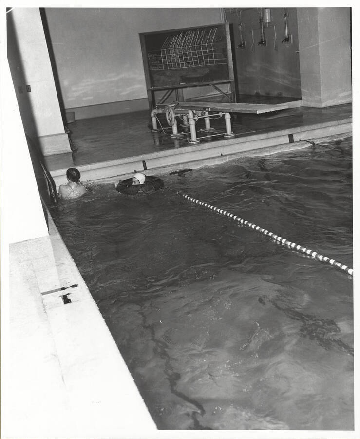 Two women's swimmers float near the edge of the Memorial Gym pool during a meet.