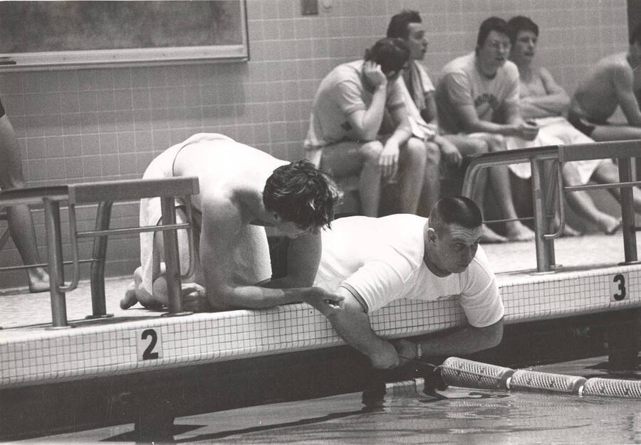 An unnamed Idaho swimmer and crew member adjust barriers at a Swim Center meet.