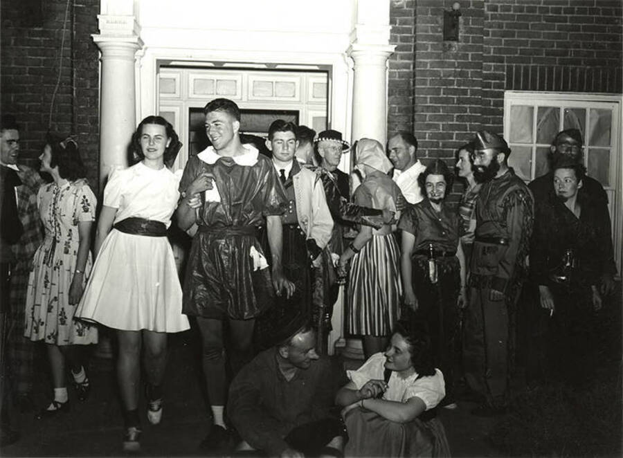 People dressed in costumes mill around and talk outside the Phi Delta Theta house during the Storybook Ball.