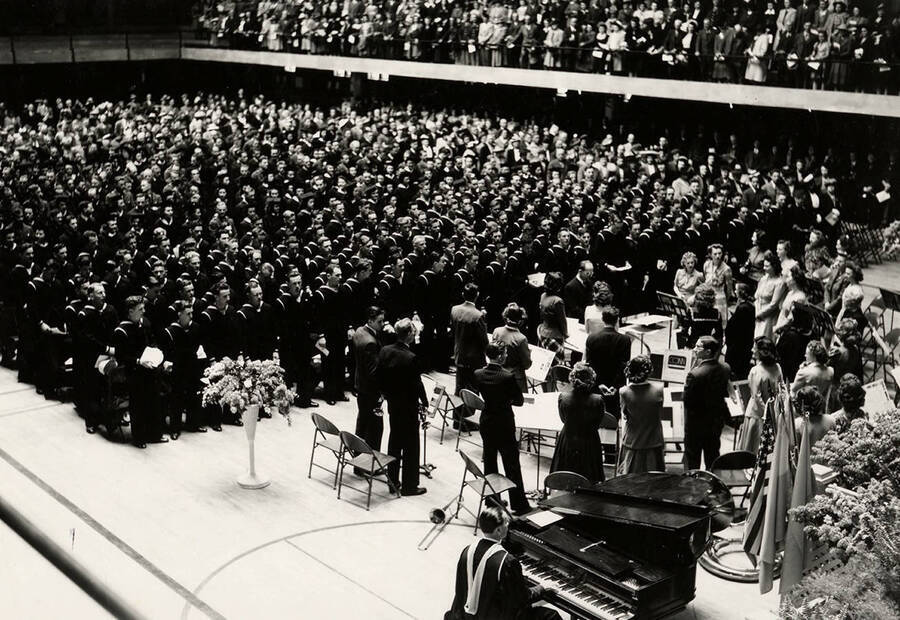 The band, graduates, and audience stand in the Memorial Gym during the  1943 Commencement ceremony.