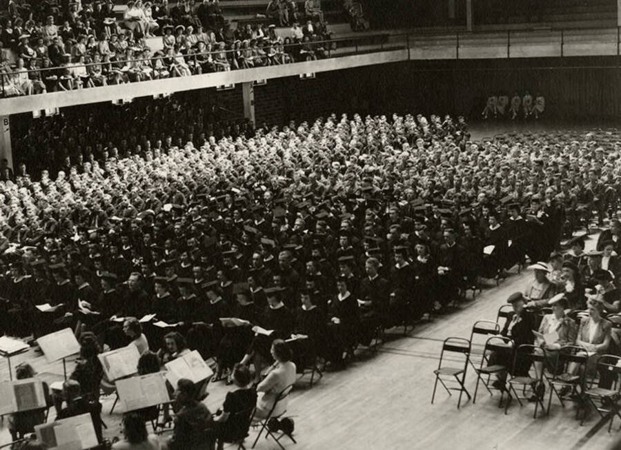 Graduates and the audience sit facing the stage during the 1945 Commencement ceremony held in the Memorial Gym.