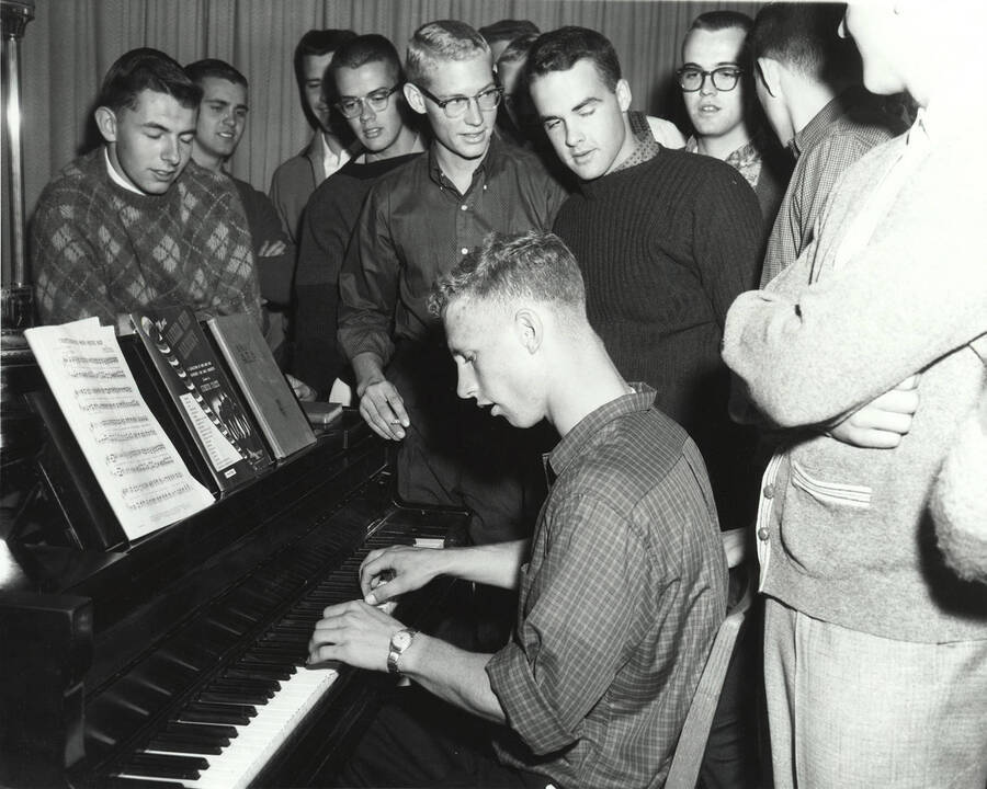Delta Tau Delta members, both current and potential, gather around another member playing the piano during rush week.