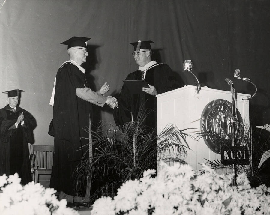 Arthur W. Fahrenwald (left) receiving a certificate of merit and faculty emeritus status from U of I President Jesse Buchanan during the 1954 Commencement ceremony.