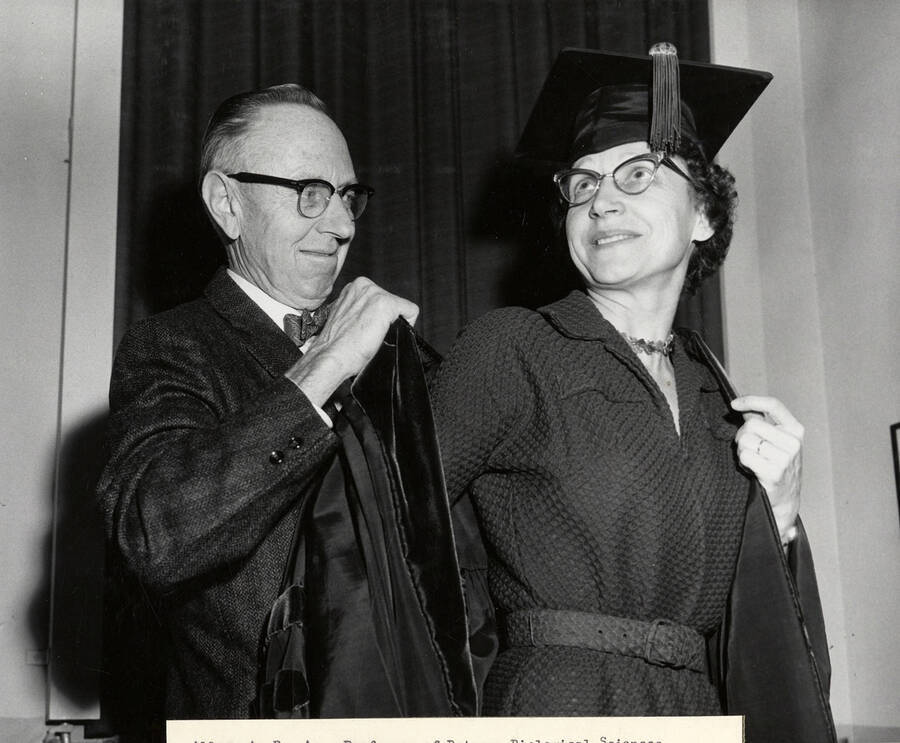 A. R. Aller, the Associate Professor of Botany, helping Florence Aller into her robe. Florence Aller is the recipient of first Doctor of Education degree at the University of Idaho.