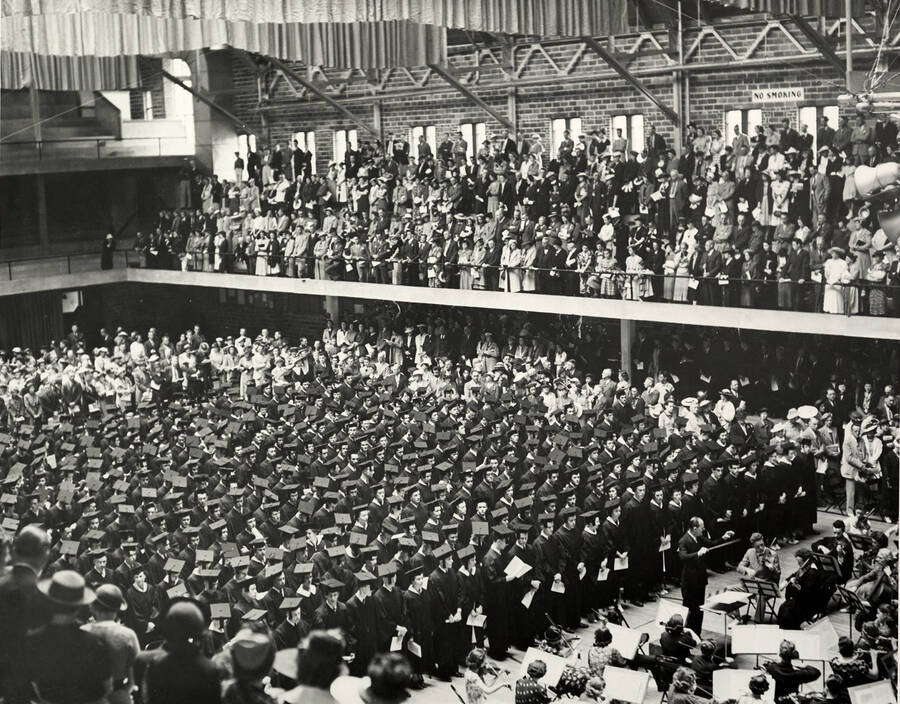 Graduates and audience stand during the 1939 Commancement ceremony in the Memorial Gym.