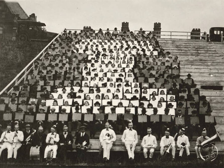 Yell Kings and dukes pose for a photograph in front of the card section of the audience at a football game.