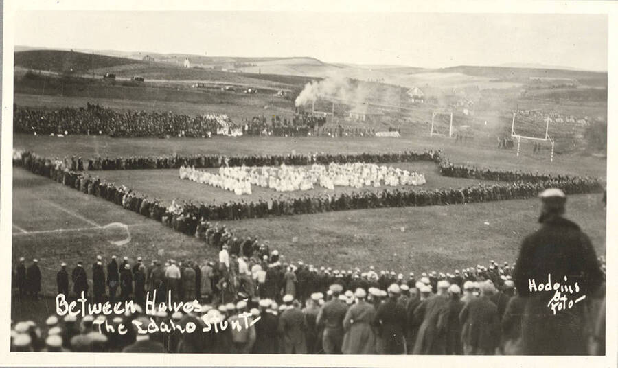 Idaho students participate in the Idaho Stunt for the Harvard Yell Contest between halves of a football game. Caption reads: Between Halves, The Idaho Stunt.