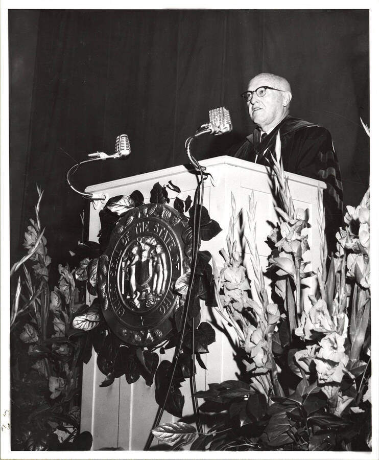 University of Idaho President Donald Theophilus speaking from the podium during the  1962 Commencement. Photographer Publications Department