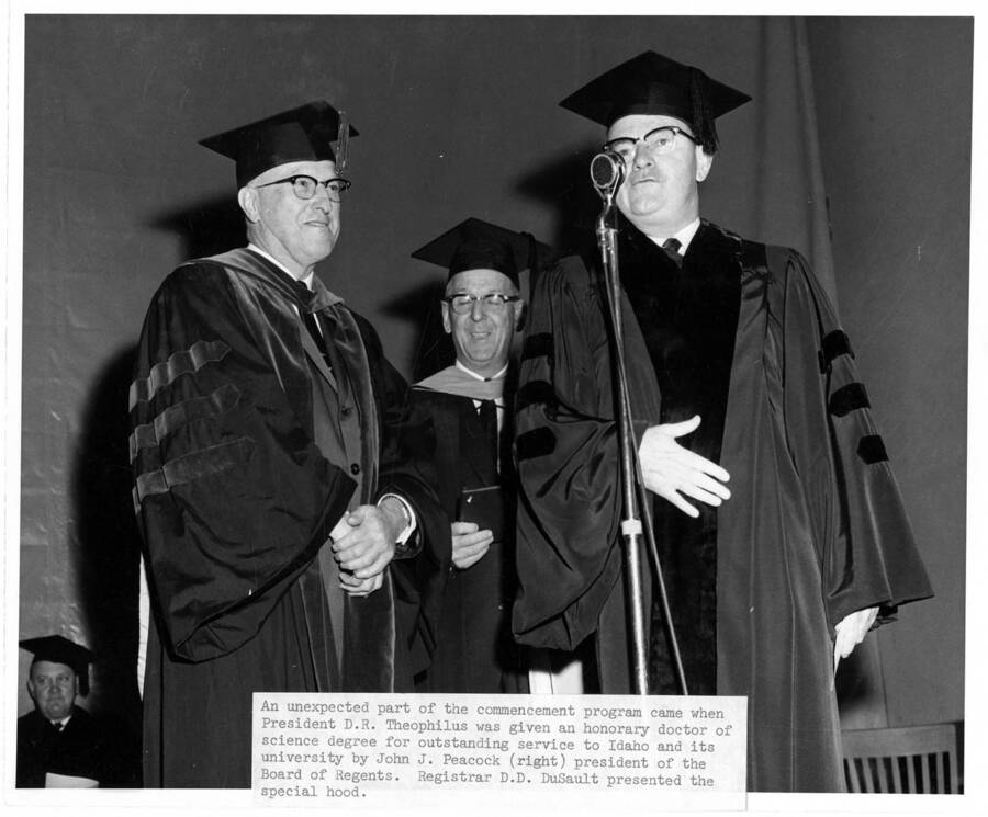University of Idaho President Donald Theophilus receives an honorary Doctor of Science degree from John J. Peacock (right), president of the Board of Regents during the 1961 Commencement ceremony. Photographer Publications Department; Registrar Donald Dudley DuSault presented the special hood.